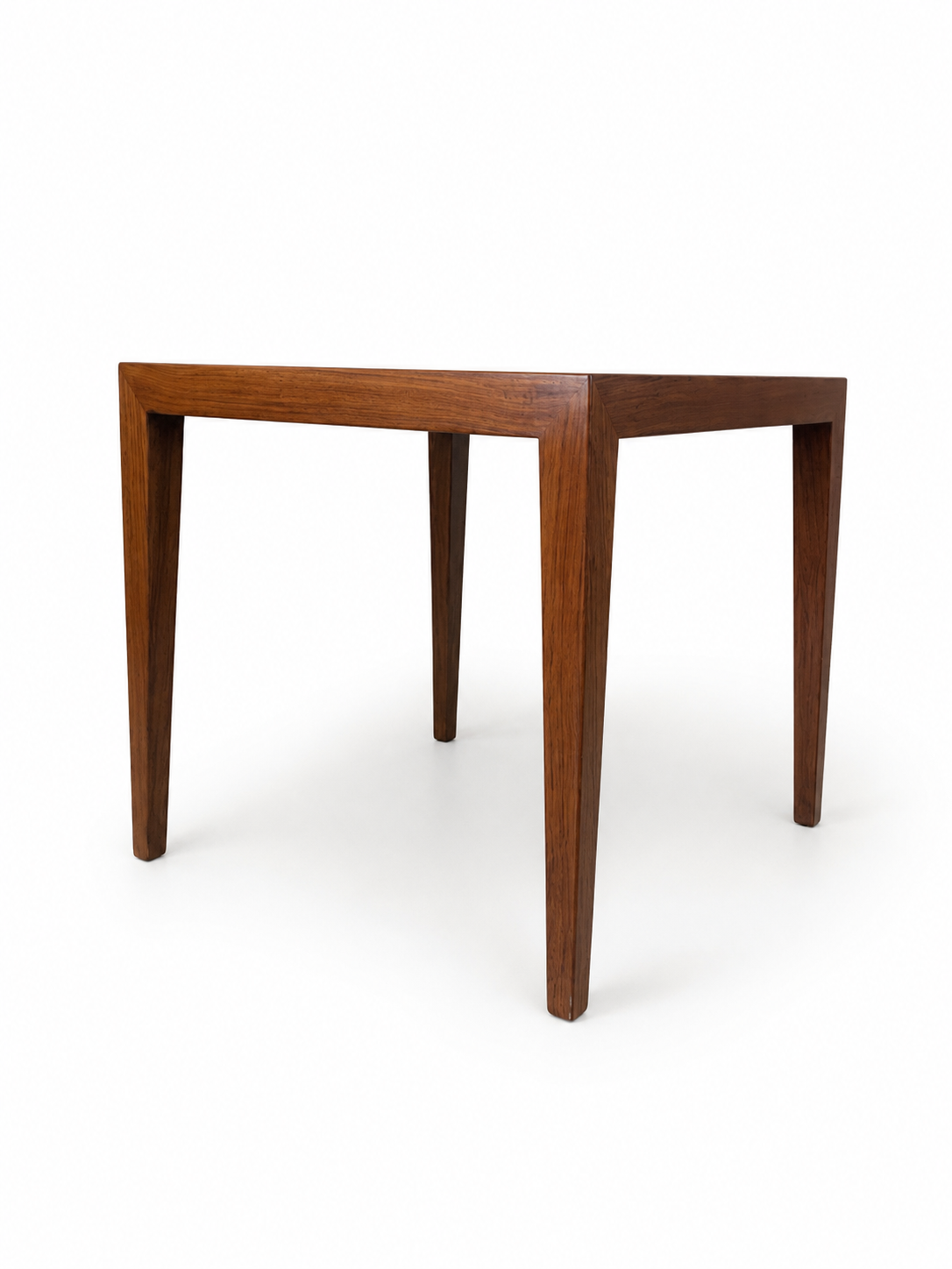 A mid-century modern wooden table with tapered legs and a square top, shown from a three-quarters angle on a white background.